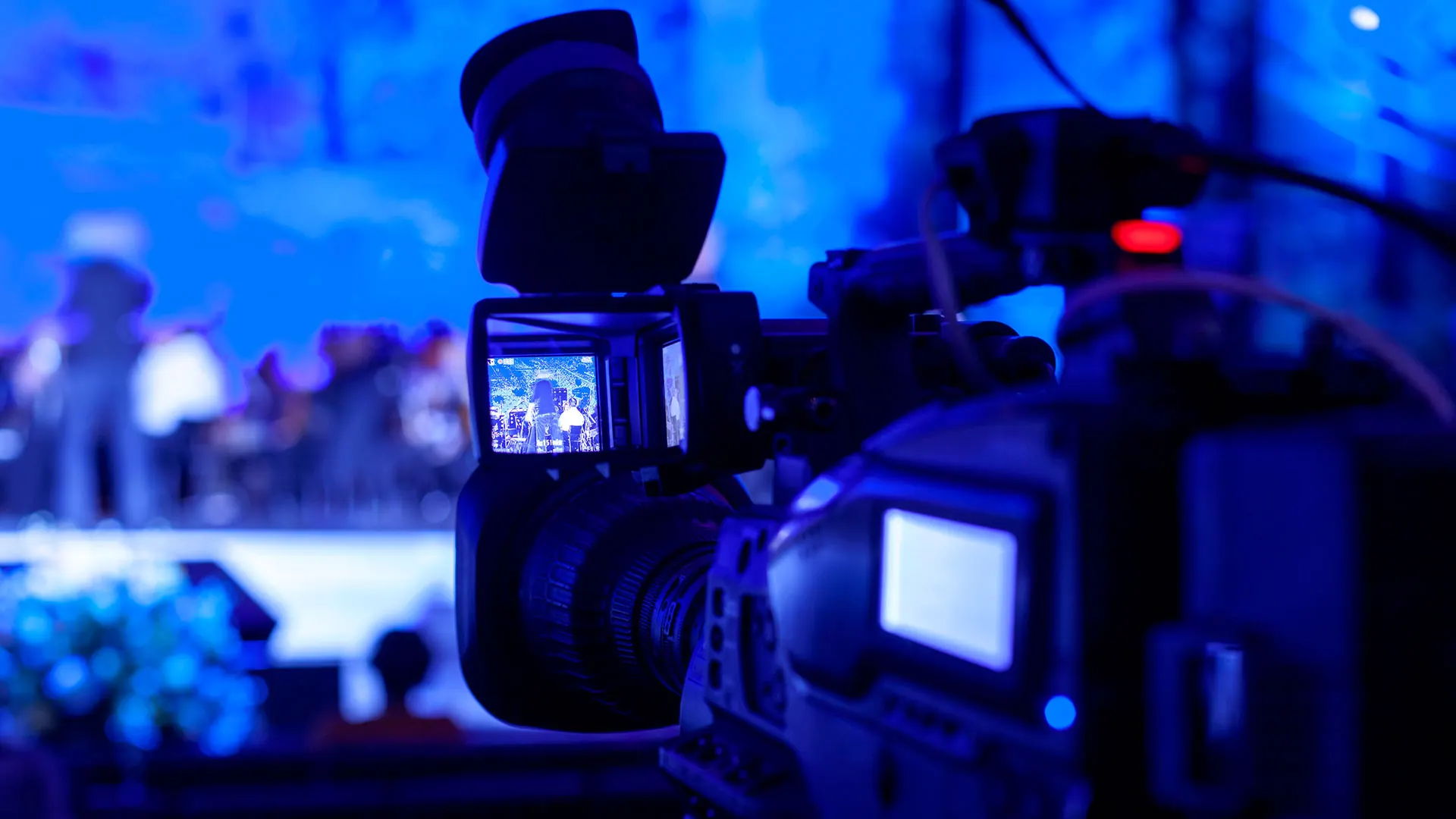 Eine Profi-Videokamera vor einer blau beleuchteten Bühne